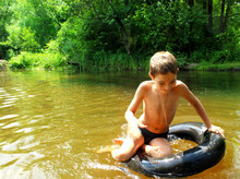The Boy Has Fun On An Inflatable Tubing In The River.