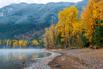 Wall Mural - Lake shore in autumn colors with a dusting of snow on mountain background, Glacier Park, Montana