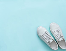 White Leather Sneakers On Blue Background. Pair Of Fashion Trendy White Sport Shoes Or Sneakers With Copy Space For Text Or Design. Overhead Shot Of New White Sneakers. Top View Or Flat Lay.