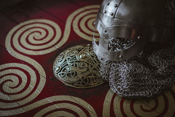 Weapons Viking helmet with chain mail of iron on red shield of wood and golden triskel