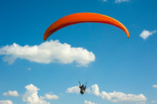 One Paraglider Is Flying In The Blue Sky Against The Background Of Clouds. Paragliding In The Sky On A Sunny Day.