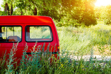 Red Van On The Background Of Green Trees And Bushes Off-road