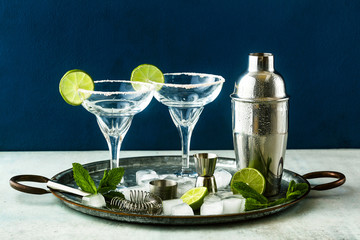 empty margarita cocktail glasses on a table with bar accessories