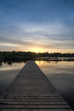 Fototapeta Pomosty - Pier stretching into the lake on a background of dawn. Vertical frame