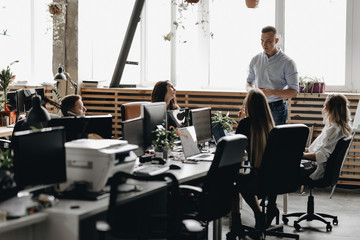 Staff meeting of a young successful team in the light modern office equipped with modern office equipment