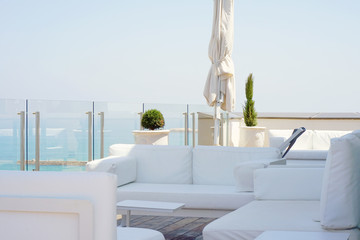 Interior of a large hotel balcony, villas. Beautiful balcony with white divans. White interior concept of a large balcony balcony. White color view of the morning horizon of the sea, the ocean.