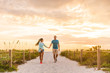 © Maridav - Happy young couple in love walking on romantic beach stroll at sunset. Lovers holding hands on Florida vacation holidays. People walking on summer evening lifestyle.