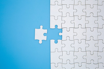 Wall Mural - Unfinished white jigsaw puzzle pieces on blue background, The last piece of jigsaw puzzle, Copy space.