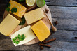 Large variety of cheese with lemon and lime laid on a round cutting Board, also parsley, spices and a spoon of honey on rustikalnom the table
