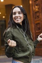 Wall Mural - Smiling portrait of a young woman enjoying while listening music on phone