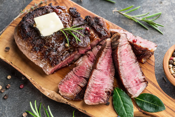 Wall Mural - Medium rare Ribeye steak with herbs and a piece of butter on the wooden tray.