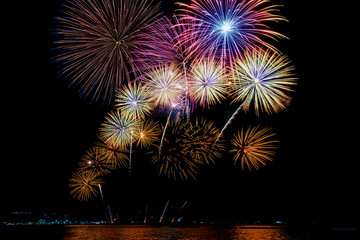 Amazing beautiful colorful fireworks display on celebration night, showing on the sea beach with multi color of reflection on water