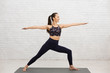 © Prostock-studio - Slender Girl In Yoga Asana On Mat Against Brick Wall
