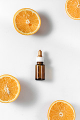 Bottle citrus essential oil and fresh juicy orange fruit on white background. High dose vitamin c synthetic for skin. Flat lay, top view, copy space