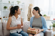 © PR Image Factory - young best female friend visit bestie giving gift box cardboard to pregnant woman sitting on sofa couch. Happy mother in living room at home. Pregnancy and motherhood expect baby friendship concept.