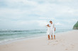 © Smeilov - Girl and man in white clothes walking on white beach in Bali and holding hands