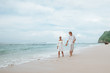 © Smeilov - Girl and man in white clothes walking on white beach in Bali and holding hands