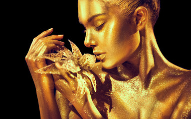 Wall Mural - fashion model woman with bright golden sparkles on skin posing, fantasy flower. portrait of beautifu