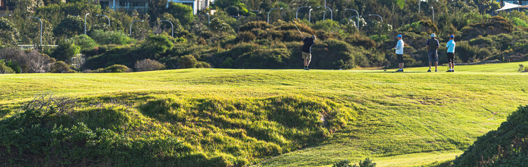 a group of golfers hitting a ball to the hole