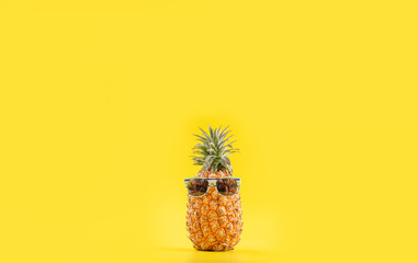 Wall Mural - Creative pineapple looking up with sunglasses and shell isolated on yellow background, summer vacation beach idea design pattern, copy space close up