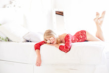A Beautiful Girl Rest In Bed Wearing A Red Lace Bodysuit In A Interior White Room