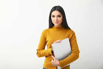 Female programmer with laptop on light background