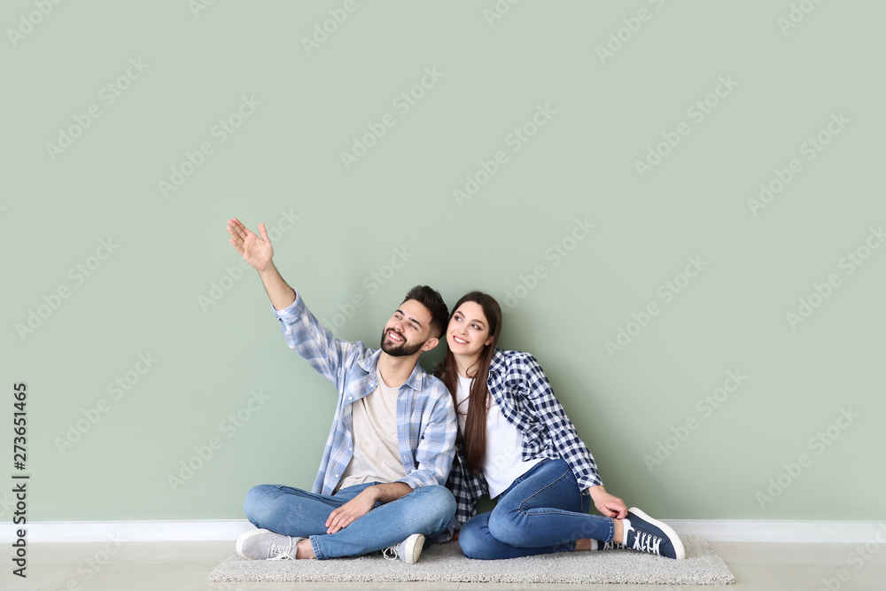 Young couple sitting near color wall