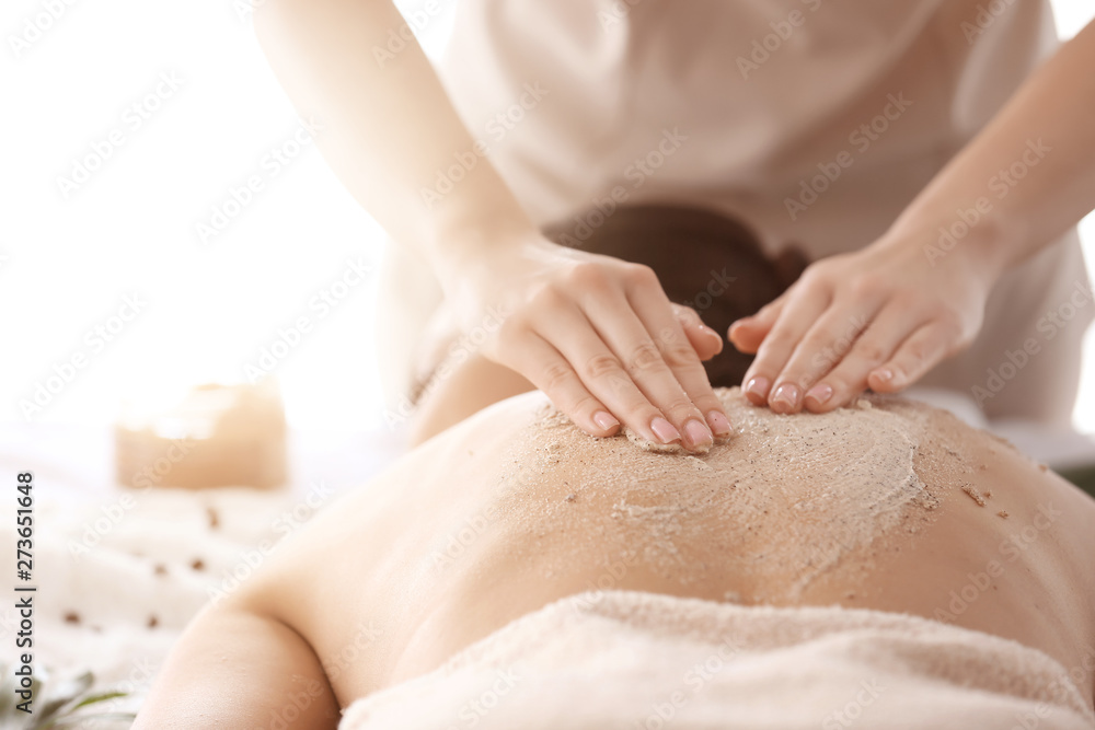 Young woman undergoing treatment with body scrub in spa salon, closeup - obrazy, fototapety, plakaty 