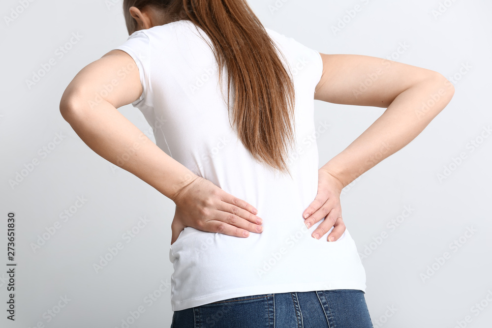 Young woman suffering from back pain on white background