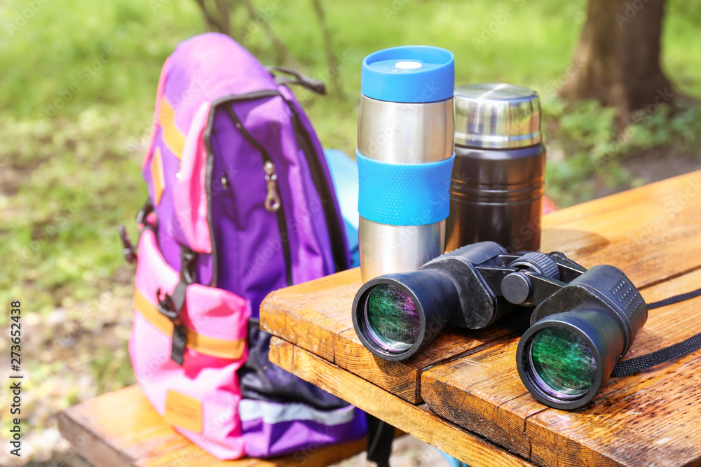 Tourist's binocular with thermoses on table in camp
