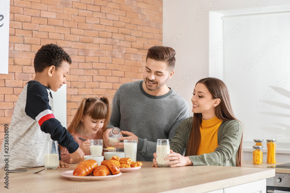 Young family drinking tasty milk in kitchen at home