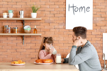 Canvas Print - Young father with little daughter drinking tasty milk in kitchen at home