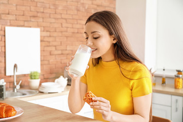 Canvas Print - beautiful woman drinking tasty milk with cookies in kitchen at home