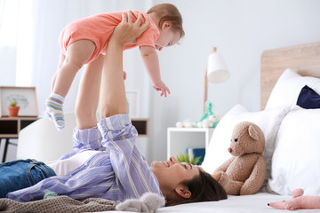 Happy mother with adorable baby boy lying on bed at home