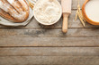 Flour with bread, milk and rolling pin on wooden background