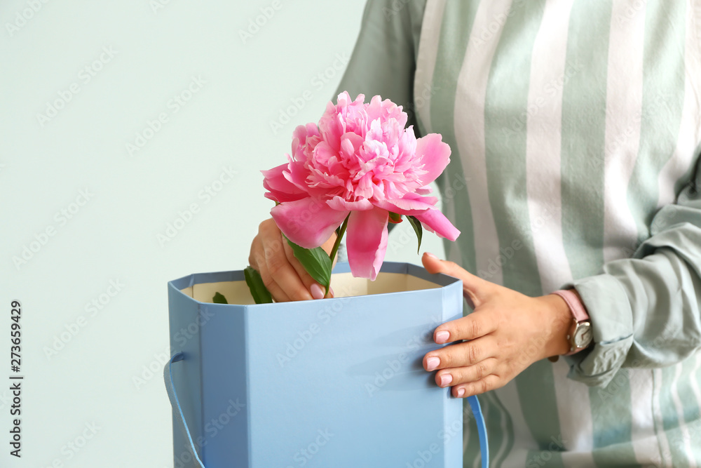 Female florist working with beautiful peonies on grey background