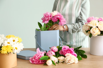 Wall Mural - Female florist working with beautiful peonies on grey background