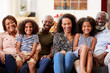 Portrait Of Smiling Multi-Generation Family Sitting On Sofa At Home Relaxing Together