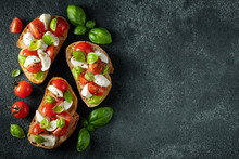 Bruschetta With Tomatoes, Mozzarella Cheese And Basil On A Dark Background. Traditional Italian Appetizer Or Snack, Antipasto. Top View With Copy Space. Flat Lay