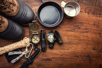 Wall Mural - outdoor travel equipment planning for a mountain trekking camping trip on wooden background. top vie