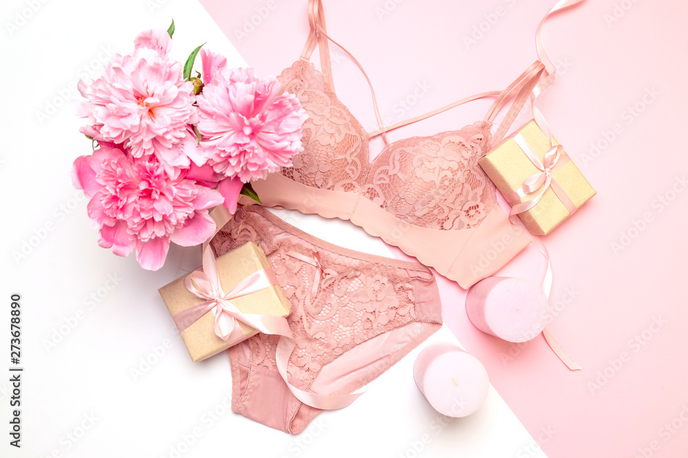 Female elegant pink lace bra and panties, flowers pink candles, a bouquet of beautiful peonies top view - obrazy, fototapety, plakaty 