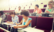 © Syda Productions - education, high school, university, learning and people concept - group of international students with notebooks writing at lecture hall