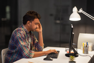 deadline, technology and people concept - stressed creative man with computer working at night office