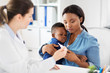 © Syda Productions - medicine, healthcare and pediatry concept - african american mother with sick baby son and caucasian doctor with thermometer at clinic