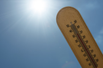 Mercury wooden thermometer shows very high temperature in celsius degree on a sunlight beams background. concept of climate warming changing problem.