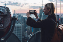 Caucasian Young Woman Traveler Making Video On Cellphone Camera While Standing On Open Observation Deck With Scenery View New York Cityscape At Sunset. Hipster Girl Tourist Enjoying Vacations In USA