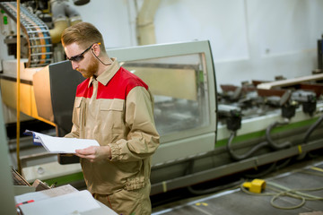 Wall Mural - Young man with blueprints working in a factory