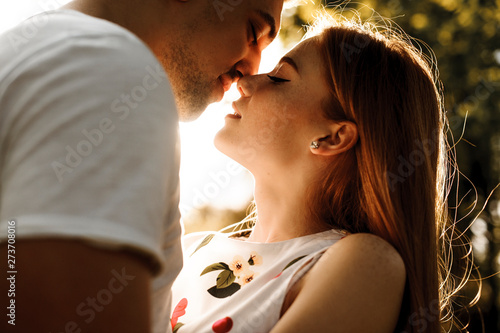 Cuadros en Lienzo Side view portrait of a amazing red haired woman with freckles kissing with her boyfriend against sunset while dating in their vacation time