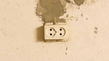 Electrical outlet on the old concrete wall. Isolated on light background.