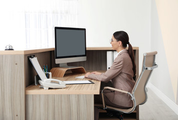 Canvas Print - Portrait of receptionist working at desk in modern hotel